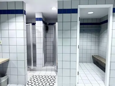 a bathroom with white tiled walls and a shower at Divya Sutra Plaza and Conference Centre, Vernon, BC in Vernon