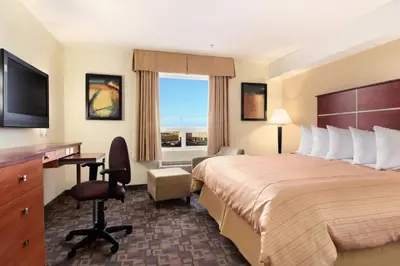 a hotel room with a bed and a desk and a window at Days Inn by Wyndham Grande Prairie in Grande Prairie