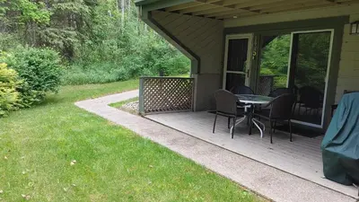 a deck with a table and chairs on a house at Akiskinook Sandy Beach Lakefront Resort! Tennis, Pickle, Basket Ball Courts, Indoor Pool, Hot Tub, Squash Court! Short Drive to Radium or Fairmont Hot Springs! in Invermere