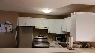 a kitchen with white cabinets and a stainless steel refrigerator at Akiskinook Sandy Beach Lakefront Resort! Tennis, Pickle, Basket Ball Courts, Indoor Pool, Hot Tub, Squash Court! Short Drive to Radium or Fairmont Hot Springs! in Invermere