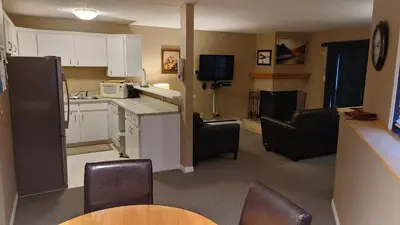 a kitchen with white cabinets and black chairs in a room at Akiskinook Sandy Beach Lakefront Resort! Tennis, Pickle, Basket Ball Courts, Indoor Pool, Hot Tub, Squash Court! Short Drive to Radium or Fairmont Hot Springs! in Invermere