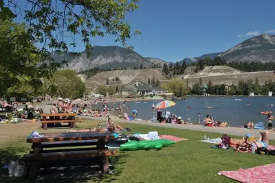 a group of people laying on the grass near a lake at Akiskinook Sandy Beach Lakefront Resort! Tennis, Pickle, Basket Ball Courts, Indoor Pool, Hot Tub, Squash Court! Short Drive to Radium or Fairmont Hot Springs! in Invermere