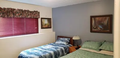 a bedroom with a bed and a window with a bedskirts at Akiskinook Sandy Beach Lakefront Resort! Tennis, Pickle, Basket Ball Courts, Indoor Pool, Hot Tub, Squash Court! Short Drive to Radium or Fairmont Hot Springs! in Invermere