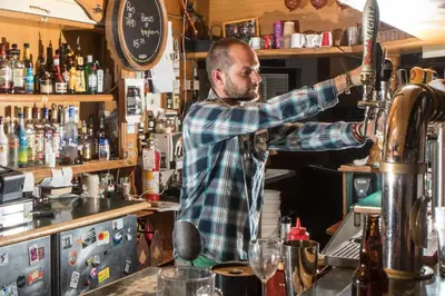 a man standing at a bar making a drink at Whistler's Inn in Jasper