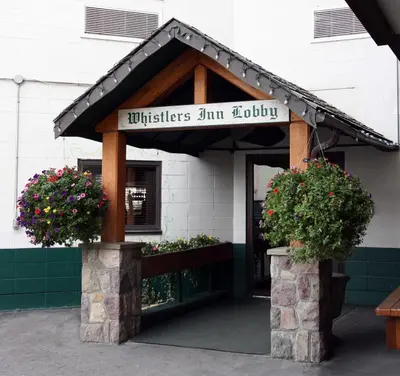 a building with a sign for a building with flowers at Whistler's Inn in Jasper