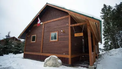 a small cabin in the snow with a rock at Cedar House Restaurant & Chalets in Golden