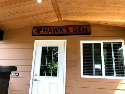 a house with a sign above a door and a sign that reads harms den at Camperland RV Resort & Cabins in Rosedale