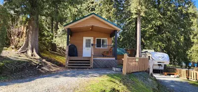 a small cabin with a porch in a forest at Camperland RV Resort & Cabins in Rosedale