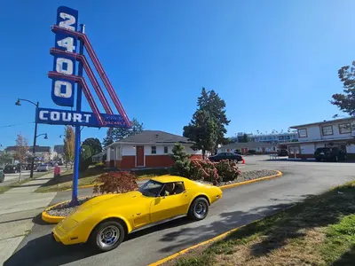a yellow car parked next to a motel sign at 2400 Motel in Vancouver