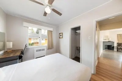 a white bedroom with a bed and a desk at 2400 Motel in Vancouver
