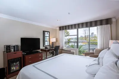 a hotel room with a bed and a flat screen tv at Granville Island Hotel in Vancouver
