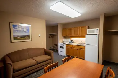 a living room with a couch and a table and a kitchen at Lobstick Lodge in Jasper