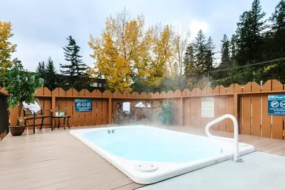 a hot tub on a deck with a wooden fence at Lobstick Lodge in Jasper