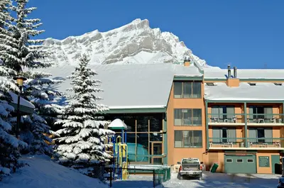 a building with a snow covered mountain in the background at Douglas Fir Resort & Chalets in Banff