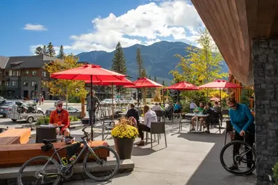 a group of people sitting at tables with red umbrellas at Banff Aspen Lodge in Banff