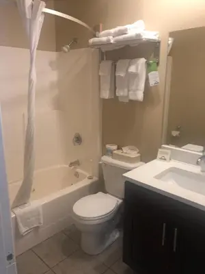 a bathroom with a toilet and a tub and a sink at Days Inn by Wyndham Hinton in Hinton