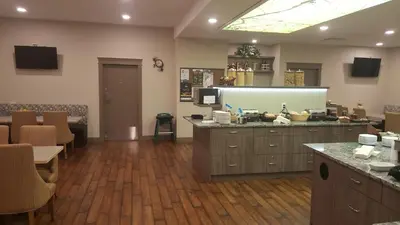 a room with a kitchen with a counter and chairs at The Royal Anne Hotel in Kelowna