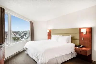 a hotel room with a bed and a large window at Victoria Regent Waterfront Hotel & Suites in Victoria