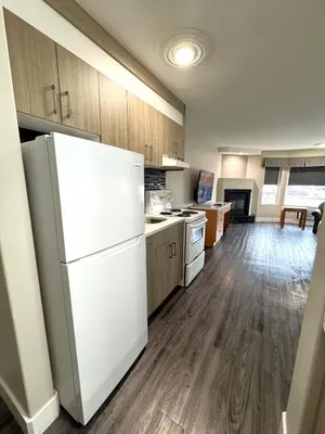 a kitchen with a white refrigerator and wooden cabinets at Western Budget Motel #1 Leduc/Nisku in Leduc