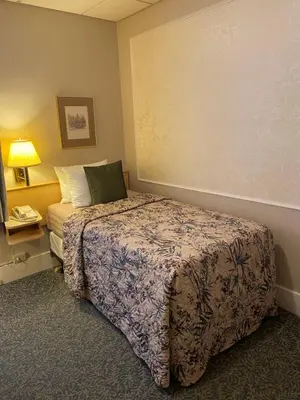 a hotel room with a bed and a lamp at Kingston Hotel in Vancouver