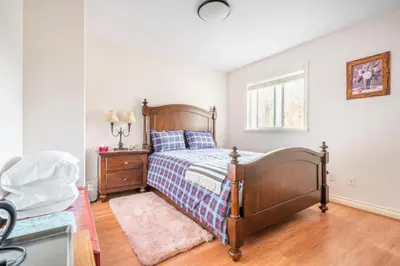 a bedroom with a bed and a dresser and a window at Fraser River Richmond Bed and Breakfast in Richmond