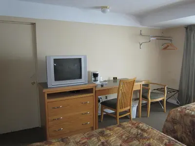 a hotel room with a desk with a television and a bed at Star Lodge in Kamloops