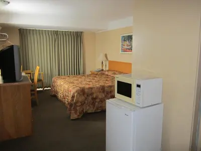 a hotel room with a bed and a microwave on a refrigerator at Star Lodge in Kamloops