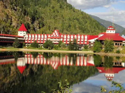 a large red and white building next to a lake at Three Valley Lake Chateau in Revelstoke
