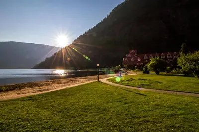 a park next to a body of water with a building at Three Valley Lake Chateau in Revelstoke