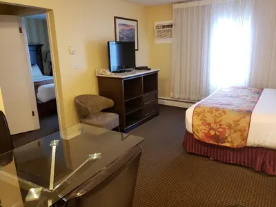 a hotel room with a bed and a desk with a television at Arbutus Inn in Victoria