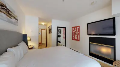 a bedroom with a white bed and a flat screen tv at Powderhorn by Whistler Blackcomb Vacation Rentals in Whistler