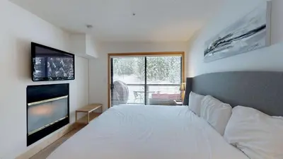 a bedroom with a white bed and a flat screen tv at Powderhorn by Whistler Blackcomb Vacation Rentals in Whistler