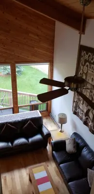 a living room with a black leather couch and a chandelier at Invermere 4 Br Lakeside, Mountain View Home! Walk to Sandy Beach for Swimming, Boating, Tennis and Beach Volleyball Local Town Shopping, Eateries, Bakery and Pubs! Welcome Family's, Healthcare Workers and Trades! Monthly Rentals of 28 Nights or More! in Invermere