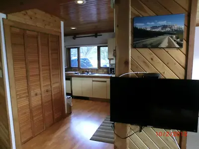 a kitchen with wooden walls and a flat screen tv at Invermere 4 Br Lakeside, Mountain View Home! Walk to Sandy Beach for Swimming, Boating, Tennis and Beach Volleyball Local Town Shopping, Eateries, Bakery and Pubs! Welcome Family's, Healthcare Workers and Trades! Monthly Rentals of 28 Nights or More! in Invermere