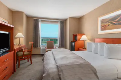 a hotel room with a large bed and a window at Days Inn & Suites by Wyndham Cochrane in Cochrane