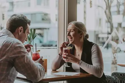 a man and a woman sitting at a table with drinks at Hotel Rialto in Victoria
