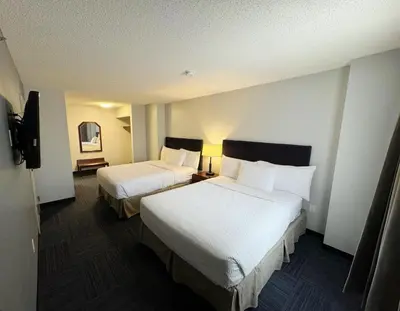 a hotel room with two beds and a television at Divya Sutra Plaza and Conference Centre Calgary Airport in Calgary