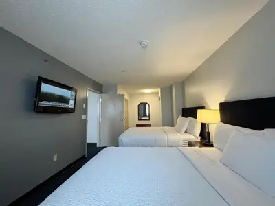 a hotel room with two beds and a flat screen tv at Divya Sutra Plaza and Conference Centre Calgary Airport in Calgary