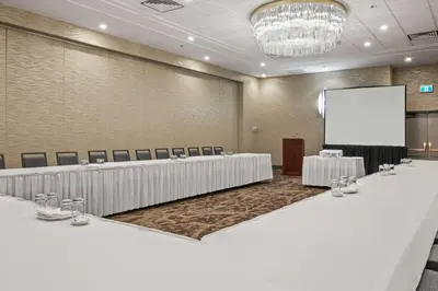 a conference room with two tables and a screen at Best Western Premier Calgary Plaza Hotel & Conference Centre in Calgary