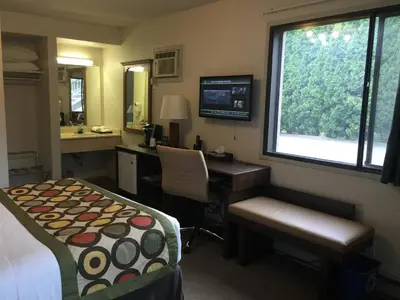 a hotel room with a desk and a bed and a desk and window at Super 8 by Wyndham Kelowna BC in Kelowna