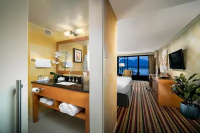 a hotel room with a bathroom with a sink and a bed at Pinnacle Hotel Harbourfront in Vancouver