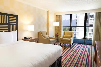 a hotel room with a bed and two chairs at Pinnacle Hotel Harbourfront in Vancouver