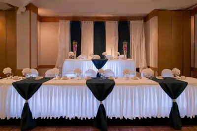 a table with white chairs and a wedding cake on it at Ramada Plaza by Wyndham Prince George in Prince George