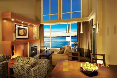 a living room with a couch and a table and a fireplace at The Beach Club Resort — Bellstar Hotels & Resorts in Parksville