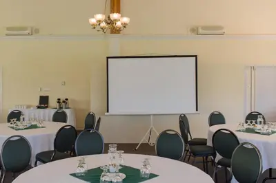 a room with tables and chairs and a projection screen at South Thompson Inn & Conference Centre in Kamloops