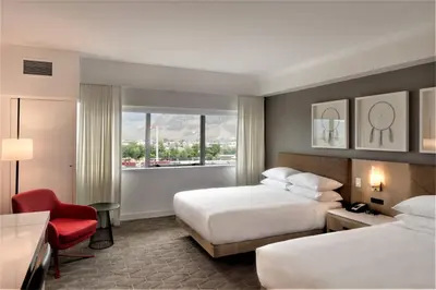 a hotel room with two beds and a red chair at Delta Hotels by Marriott Kamloops in Kamloops