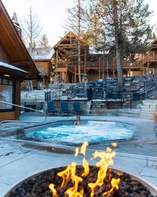 a person in a swimming pool with a fire pit at Buffalo Mountain Lodge in Banff