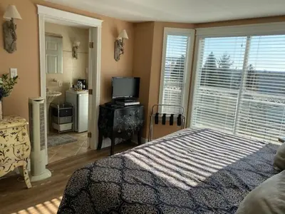 a bedroom with a bed and a television and a bathroom at Ocean Breeze Executive Bed and Breakfast in North Vancouver