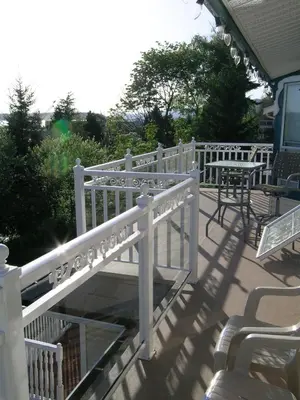 a white railing on a patio with tables and chairs at Ocean Breeze Executive Bed and Breakfast in North Vancouver