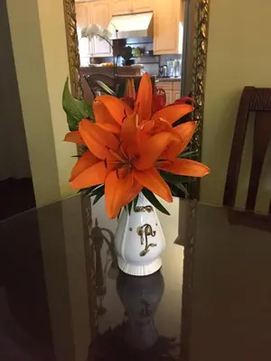 a vase filled with orange flowers in a mirror at Ocean Breeze Executive Bed and Breakfast in North Vancouver